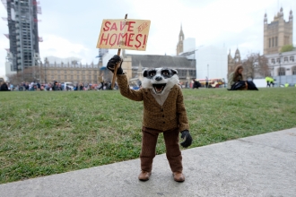 Badger from the Wind in the Willows film holds up a 'Save Our Homes!' sign 