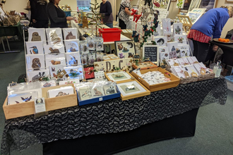 A stall full of Christmas art and craft with people milling around