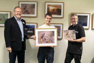 Overall photo comp 2023 winner Matt Hazleton smiles holding his framed winning image as Brian Eversham and Russ Waldron hold up his prizes