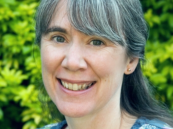 Lady with grey dark hair smiling to camera