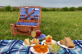 A picnic lunch laid out on a blanket on the grass