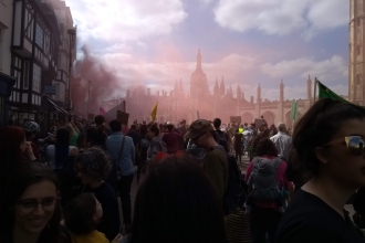 The climate strike culminates outside Trinity College, Cambridge, with symbolic smoke hanging in the air