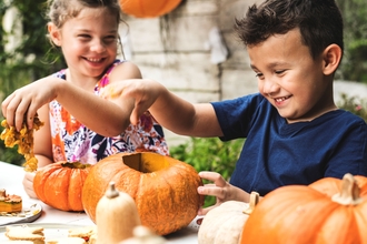 Two children carving pumpkins