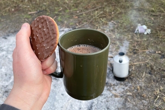 Person holding hot chocolate and biscuit