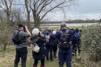 Group of people looking at lake with binoculars