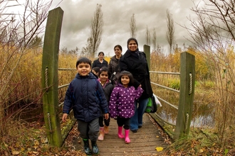 A family walking across a small bridge on an autumnal day