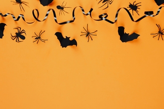 An orange screen with paper bats, plastic spiders and black ribbon