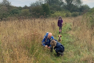 A family with a dog, on a walk through a grassy field