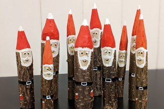 A group of jolly hazel stick santas, with bright red painted pointy hats