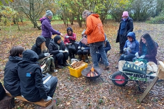 Group of young people sat around a campfire with WTBCN staff members