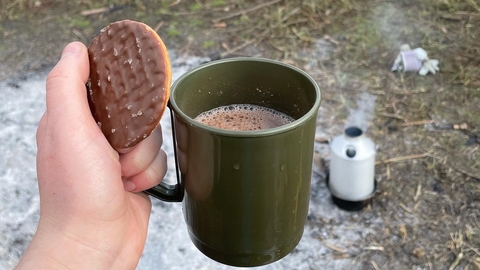 Person holding hot chocolate and biscuit