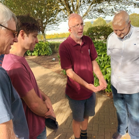 Iain, standing with a group of staff members from a corporate group, outside on a sunny day