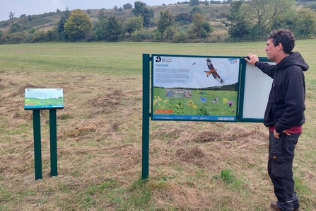 Staff member standing next to a new interpretation sign at Blows Downs Nature Reserve