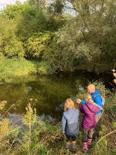 Rev'd Chad Chadwick and family standing on the edge of a pond, next to Strawberry Hill