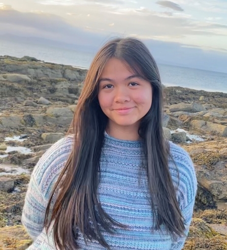 YPF member smiling at the camera standing amongst rockpools on a beach