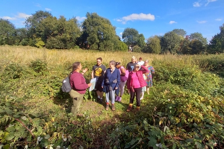 A group of people outside on a guided walk on a sunny day