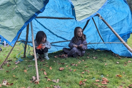 Two young children in a tarpaulin tent