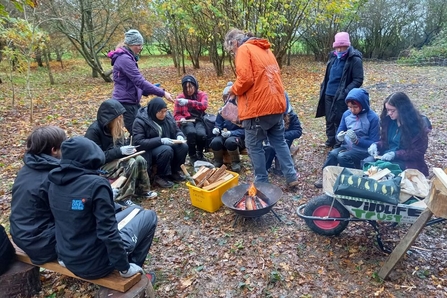 Group of young people sat around a campfire with WTBCN staff members