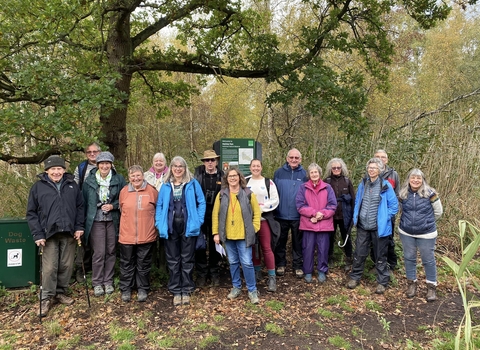 15 people from the Peterborough local group smiling at the camera on a guided walk at Holme Fen