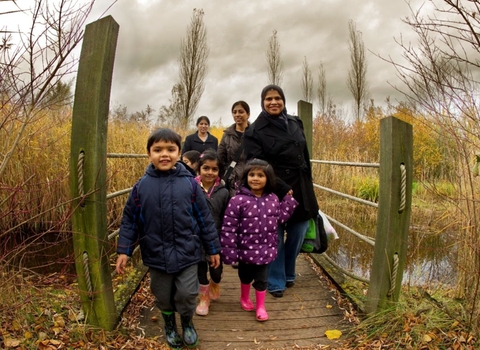 A family walking across a small bridge on an autumnal day