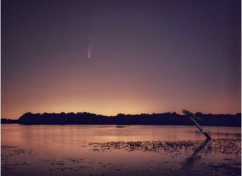 A night sky, purple and orange above Pitsford Water, with a shooting star or comet streaking above.